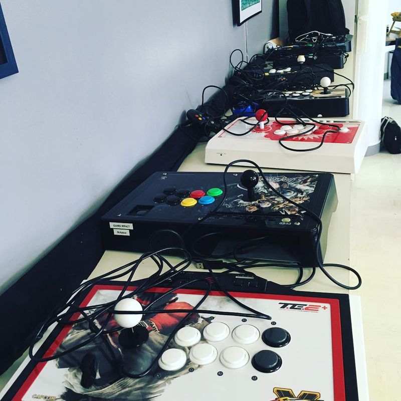 A bunch of arcade sticks on a table figcaption
