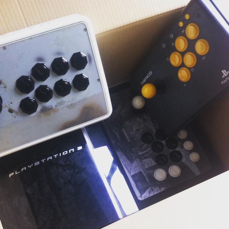Several arcade sticks in a box figcaption